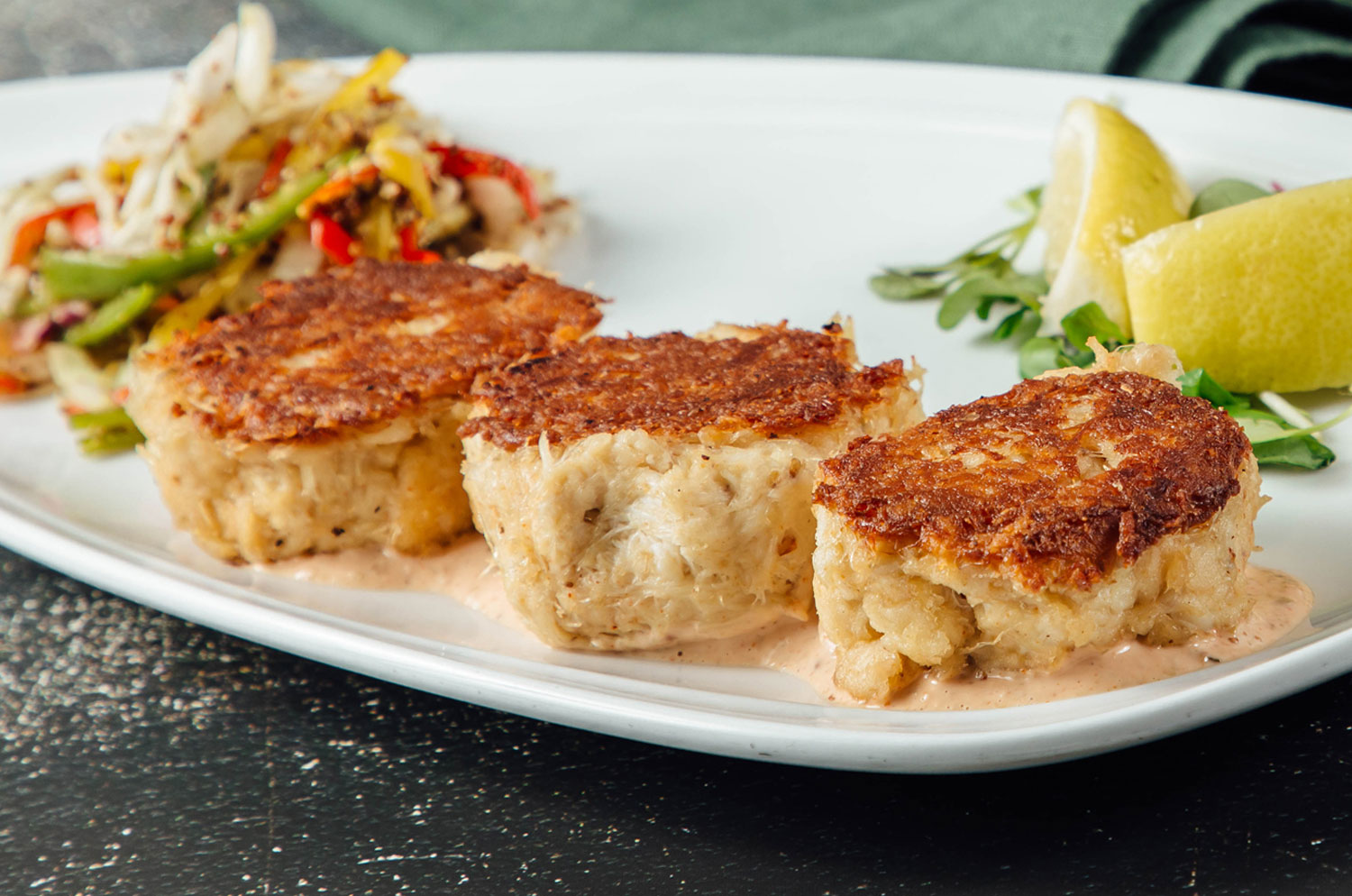 Three crab cakes featured on a plate.